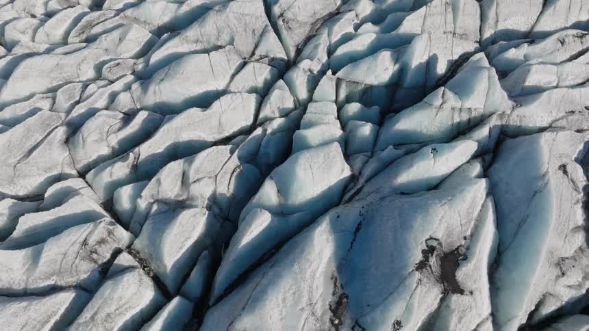 Deep crevices separate blue white glacial terrain