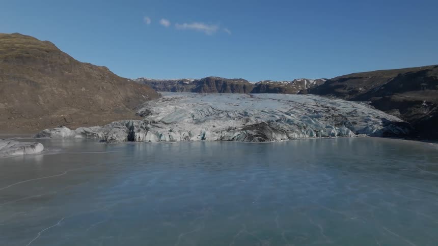 Aerial view of a big icy glacier next to a frozen lake