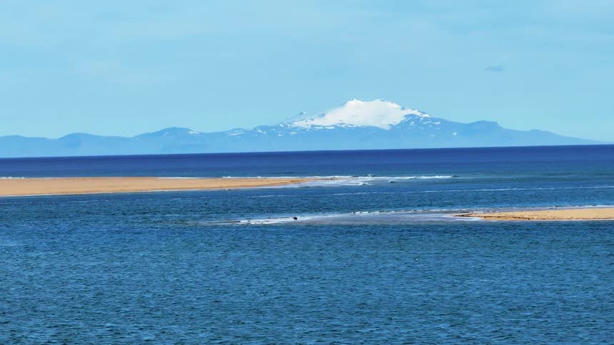 Aerial view of sandy beach and distant snowy mountain