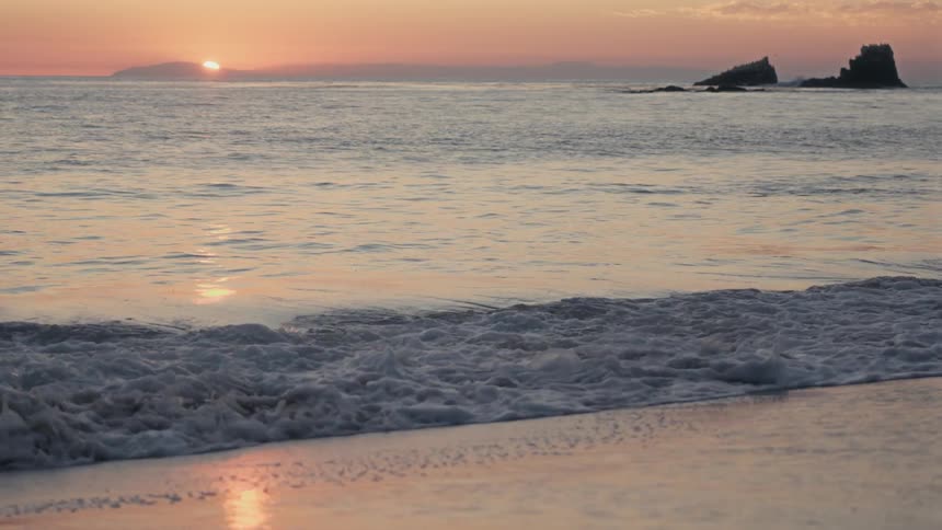 Sea waves breaking against the beach at sunset