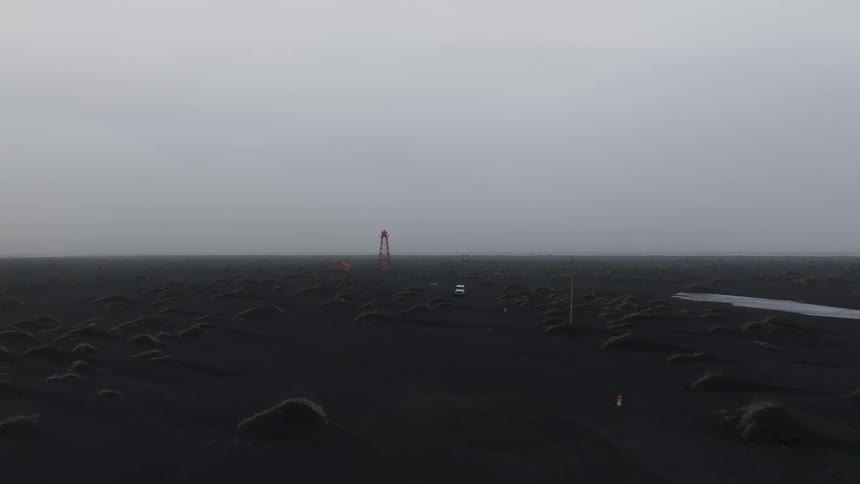 Panorama of a white jeep driving through a natural environment with black soil on a cloudy day with fog