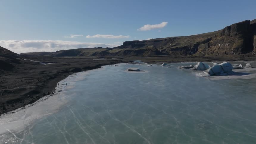 Panorama of a small frozen lake next to mountains