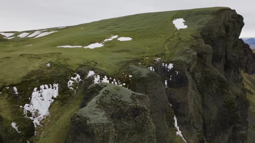 Panorama of a mountain with parts covered in snow on a cloudy day
