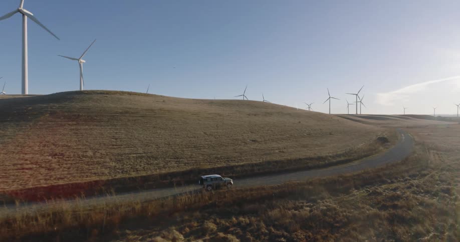A car driving along a road at a rural wind farm