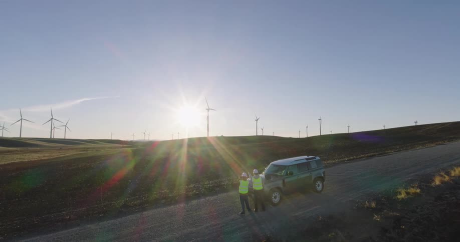 Two technicians standing on the road crossing a wind farm
