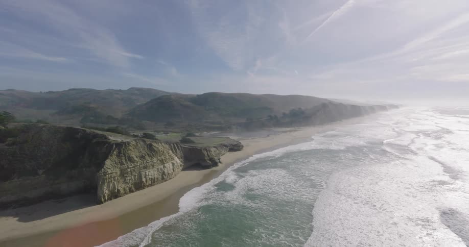 Aerial of a beach with rocky mountains during the day