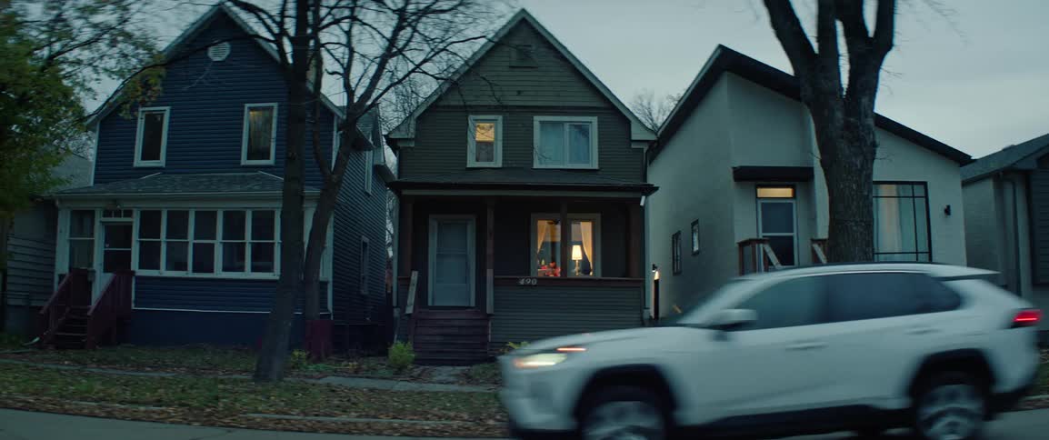 View of residential houses on a cloudy evening with a vehicle passing by on the street
