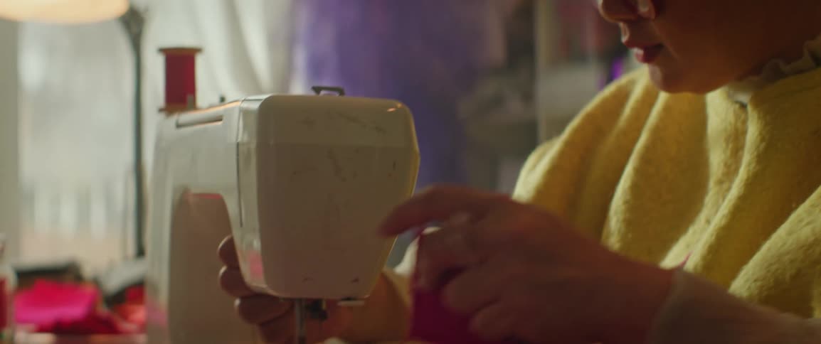 Woman operates sewing machine then cuts thread on stitching