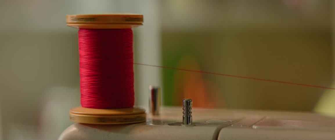A spool of red thread being used on a sewing machine