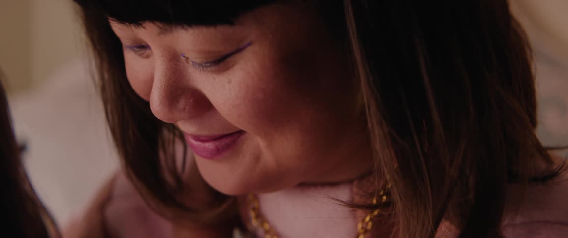 A mother smiles while listening to her daughter read a story book