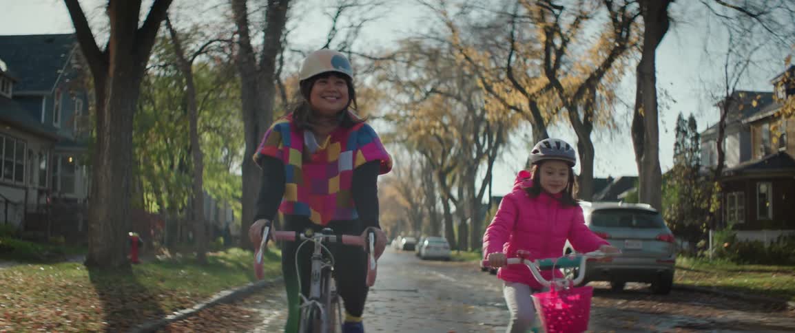 Leaves fall as a mother and daughter ride bicycles