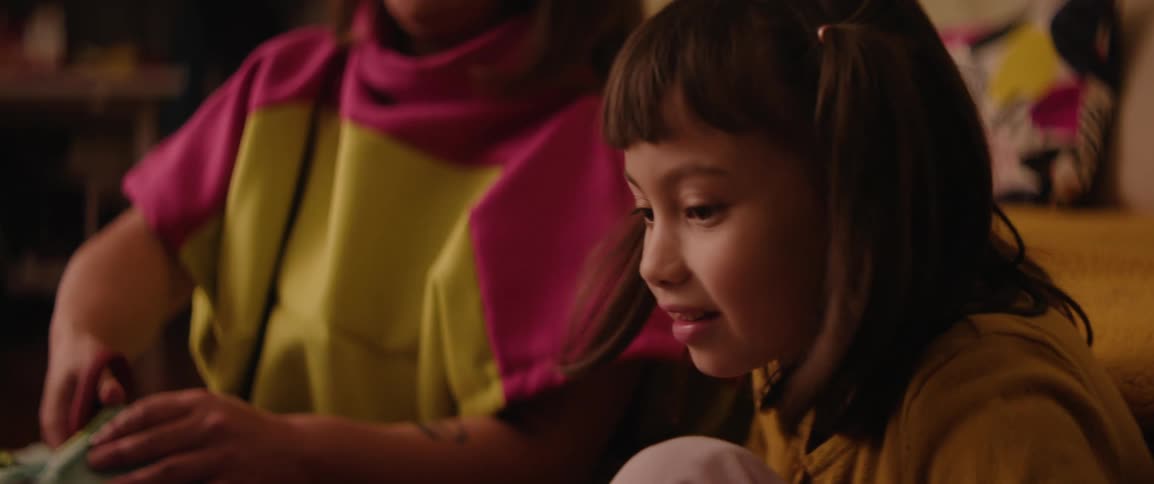 Young girl excitedly looks on as her mother prepares arts and crafts