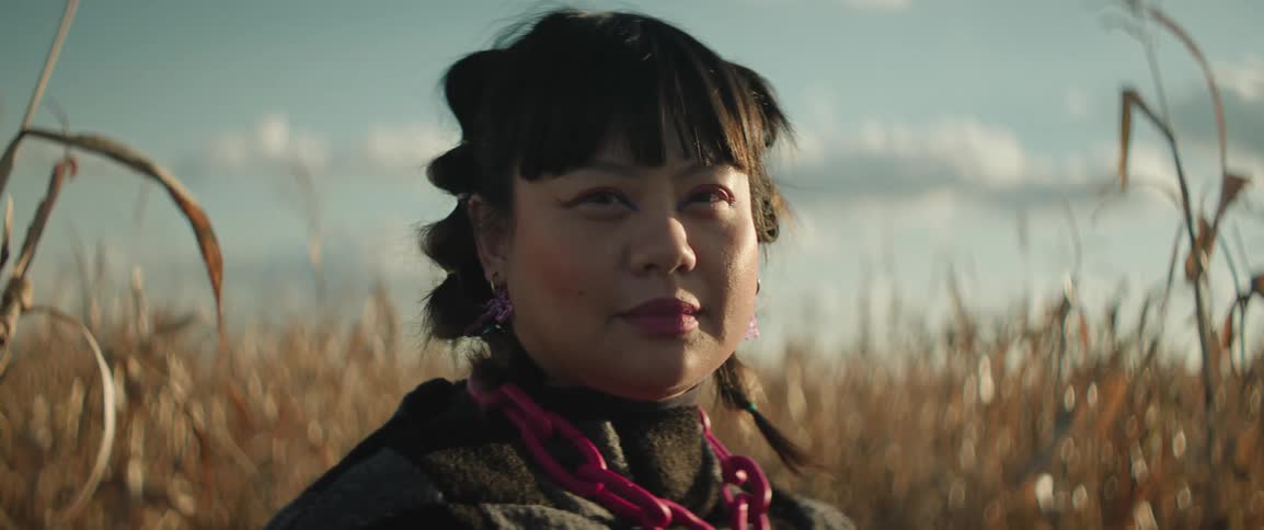 A portrait of a woman standing in a dried corn field smiling