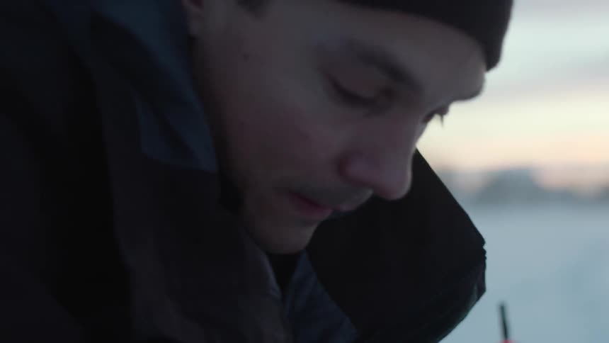 A man ice fishes in frigid weather
