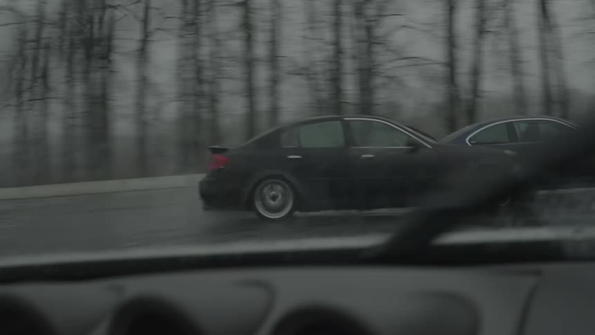 Two black cars drifting skillfully on wet roads in the rain