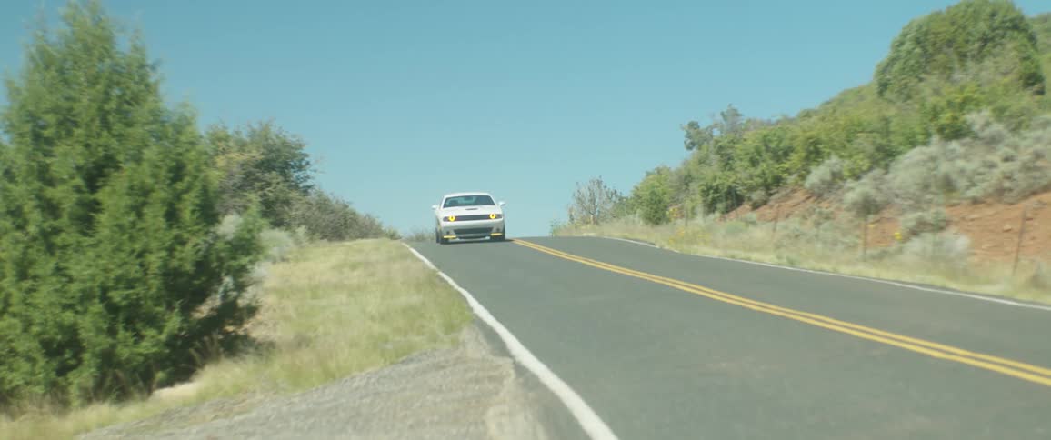 White sports car driving on a road in the countryside