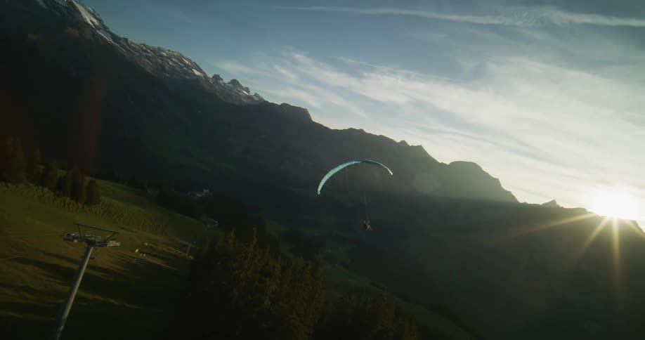 A person skydiving in a region with mountains on a morning with the sun rising