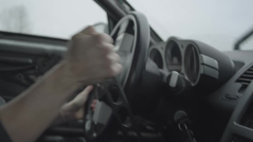 A person turning a car steering wheel quickly