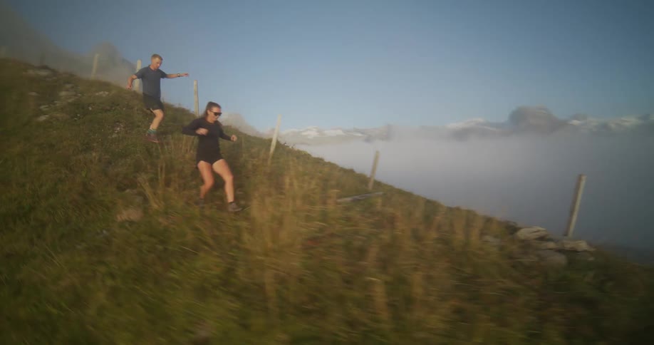 Two people running down the hill covered in mist