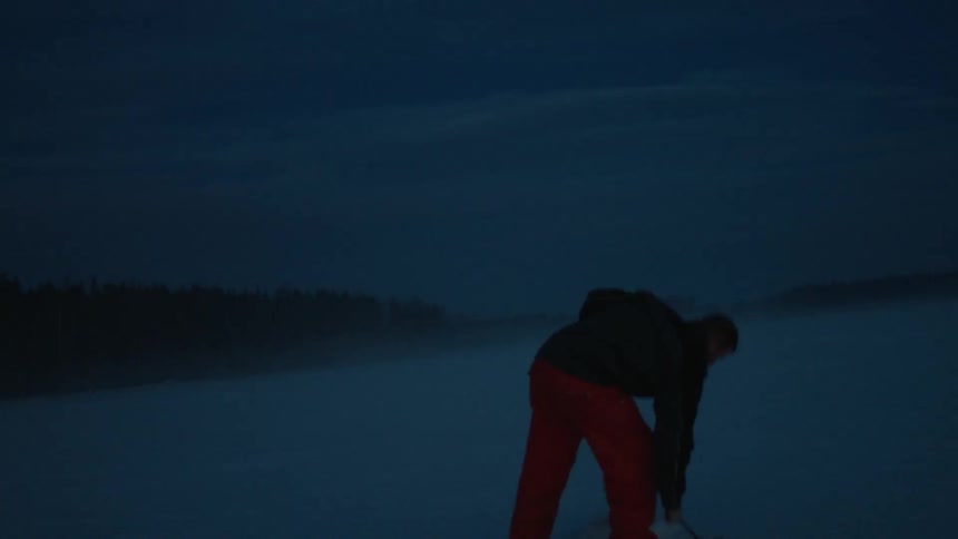 An ice fisherman uses a corkscrew tool to bore out a fishing hole