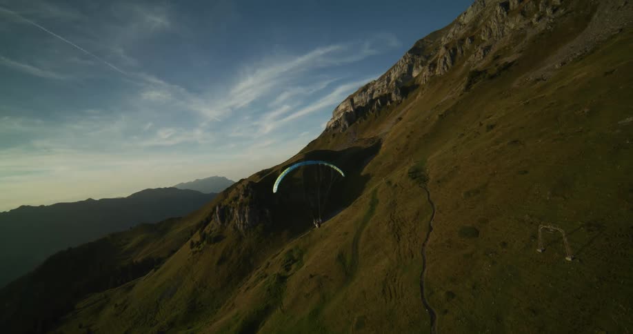 A person skydiving near hills on a bright sunny morning