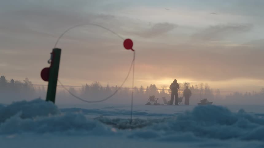 Two men ice fish at sunset