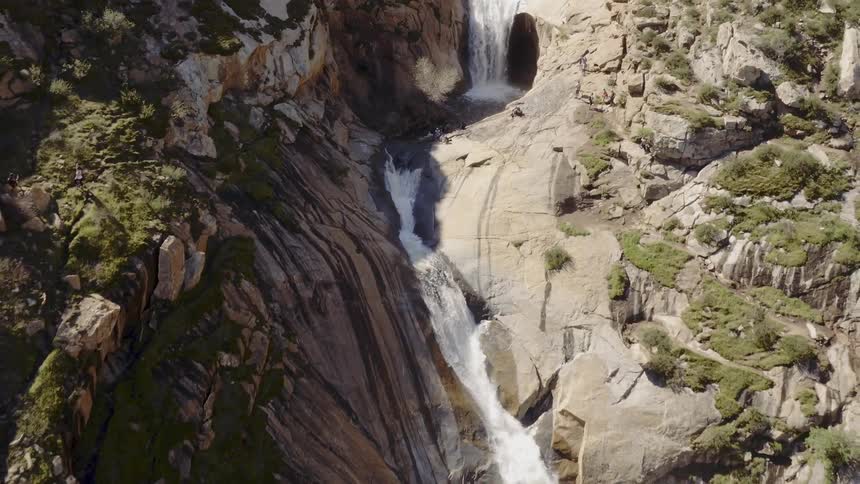 Water falls from a cliffside and flows down the mountain