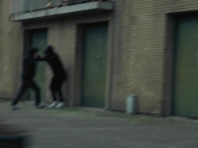 Passing along street past men fighting in apartment parking lot