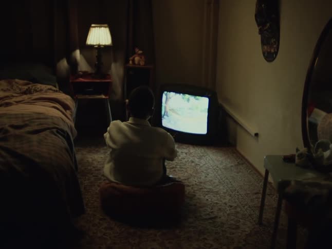 A kid watching a tv show in the bedroom