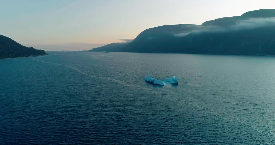 Panorama of small icebergs in the sea with mountains on the sides under a morning sky