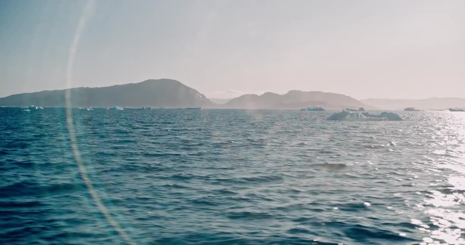 View of the sea with small icebergs and mountains on the horizon