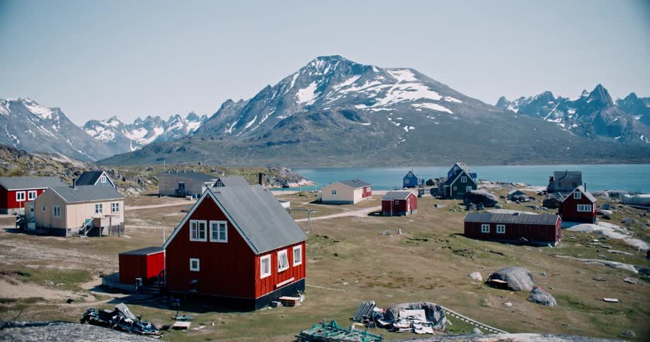 Colorful houses amid coastal fields with icy mountains in the surroundings