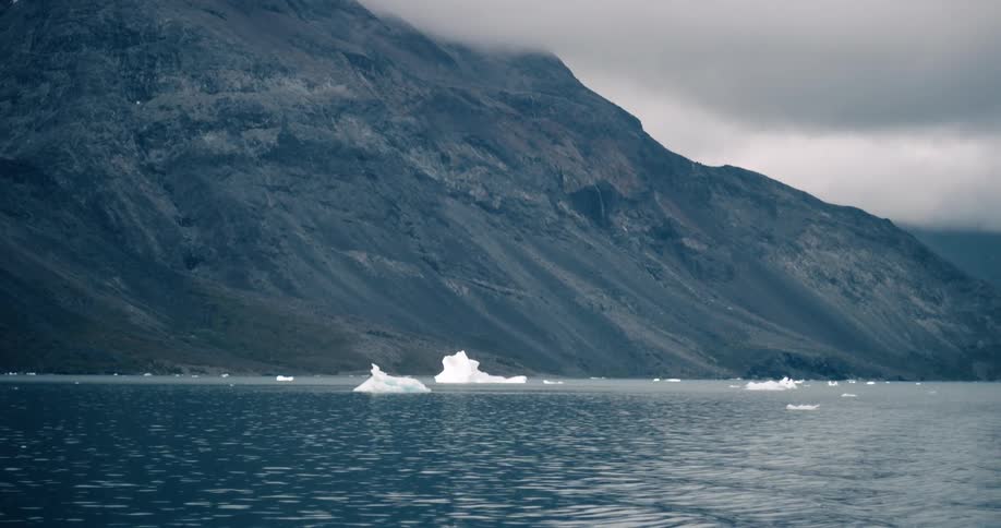 Iceberg floating on a lake next to the mountains