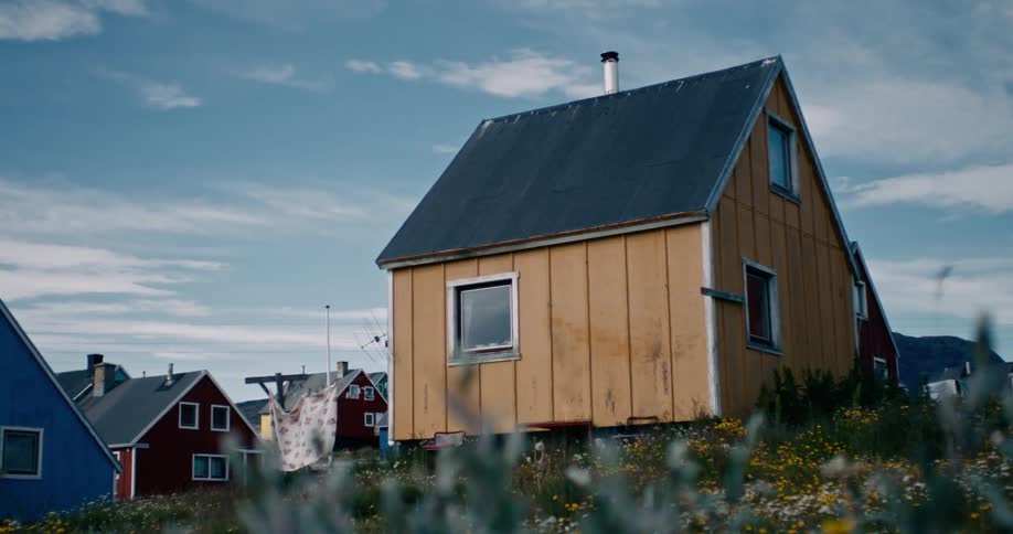 A house under construction at the edge of a colorful neighborhood