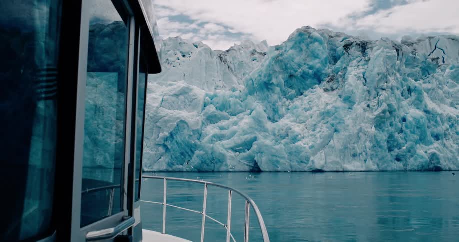 Seagulls flying next to a glacier seen from a boat