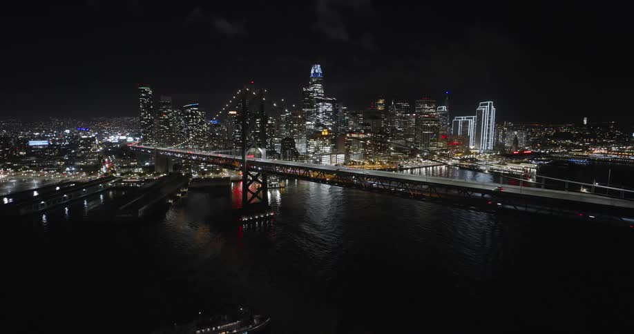 Aerial view of a bridge and night lights in a waterfront city