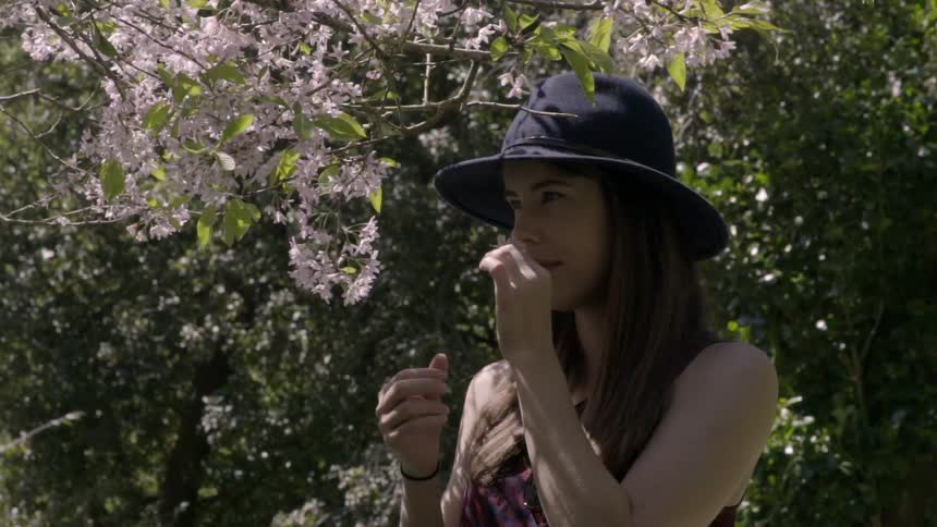 A woman smelling a tree blossom