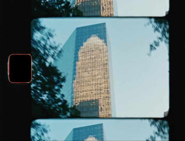 Building reflected on surface of blue tinted skyscraper forms pattern in white