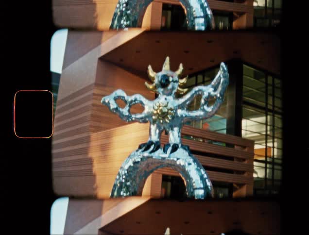 Silver colored metal sculpture stands in plaza near an office building