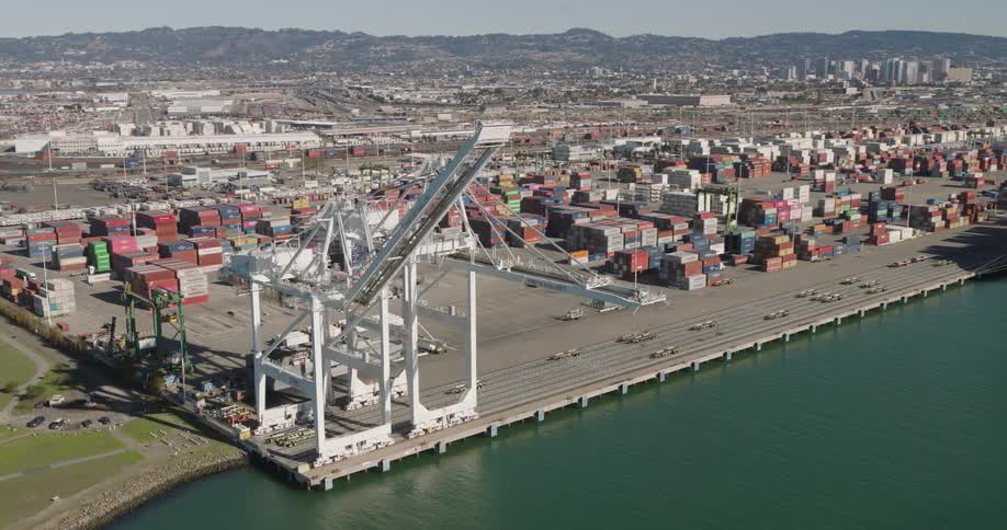 Container ship sits at loading dock with city skyline in the background