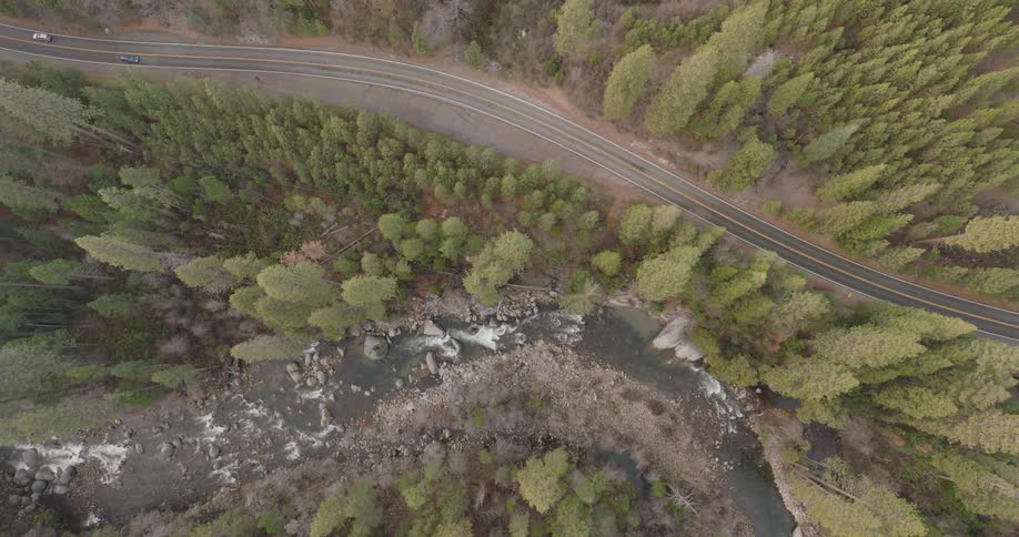 Aerial of a deserted road between forest and river during the day