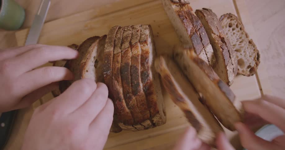 People taking slices of bread from a cutting table