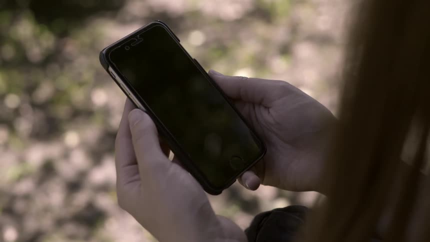 Girl looks down at the black screen of a smartphone