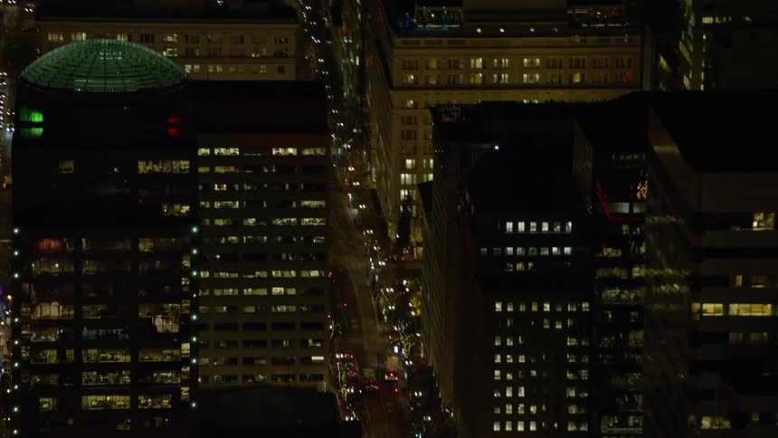 Vehicles pass through downtown intersectins at night