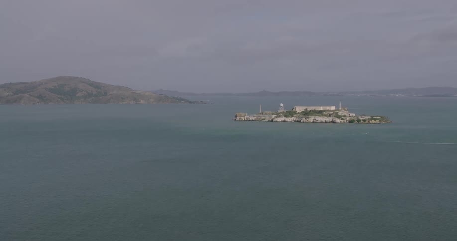 Aerial panorama of an island amidst the sea with a mountain range on the horizon
