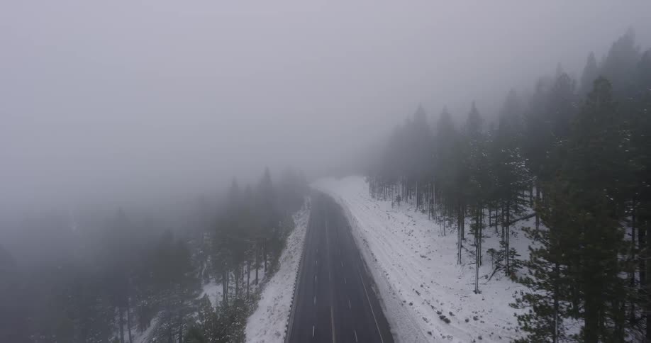 Light traffic moves on a mountain forest road on a foggy winter day