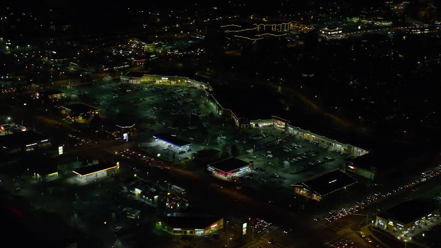 Traffic flows along city streets near shopping mall at night