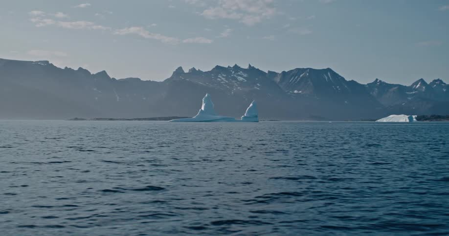 Iceberg floating in the sea near a mountain
