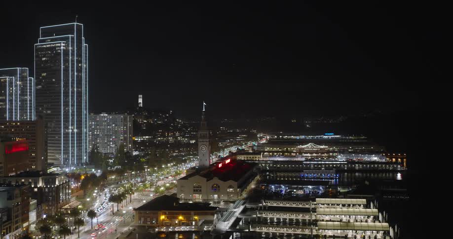 Traffic passes between downtown skyscrapers and waterfront docks at night