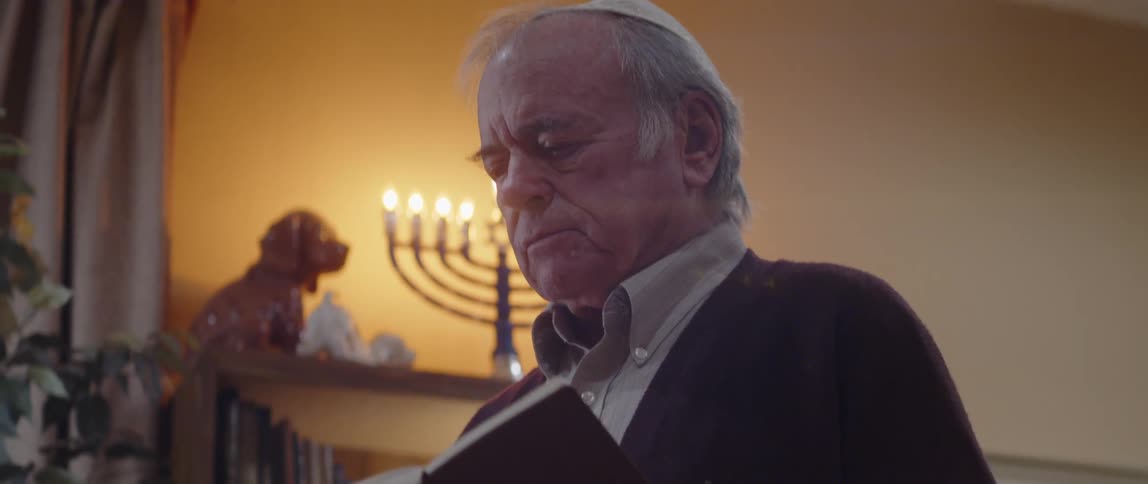 A jewish elderly man reading from a book during a religious ceremony